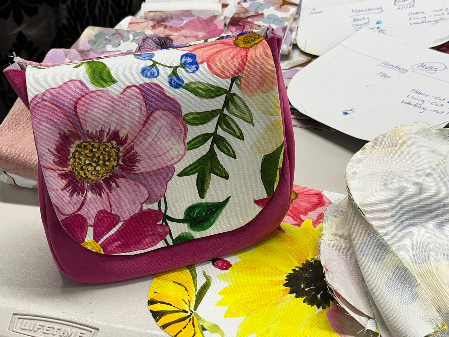 Floral-patterned hand bag on a table with other floral items