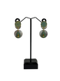 Pair of earrings on a black stand against a white background