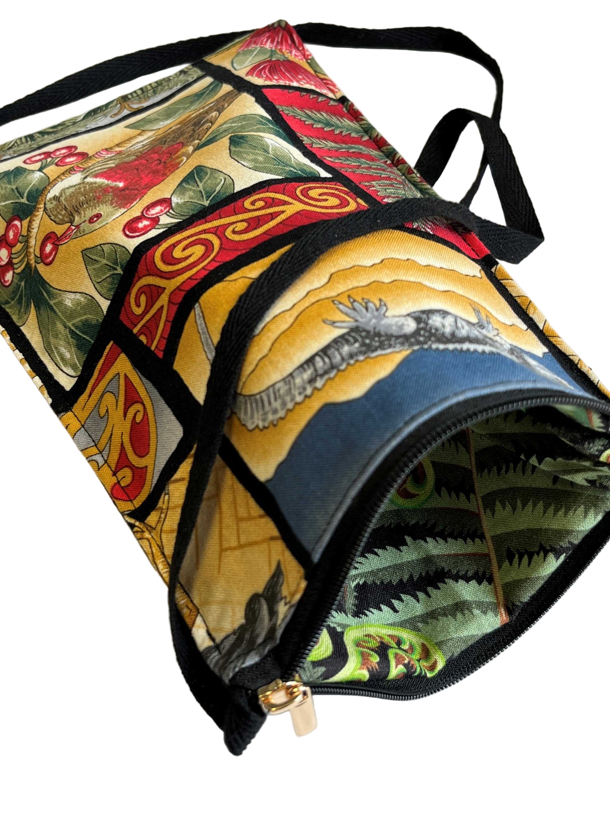 Close-up of Kiwiana phone bag showing zipper detail and green fern-printed lining, with black strap visible.