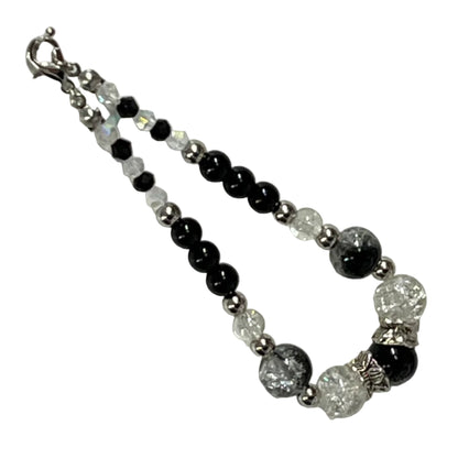 Beaded bracelet with black, white, and silver beads on a light gray background