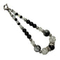 Beaded bracelet with black, white, and silver beads on a light gray background