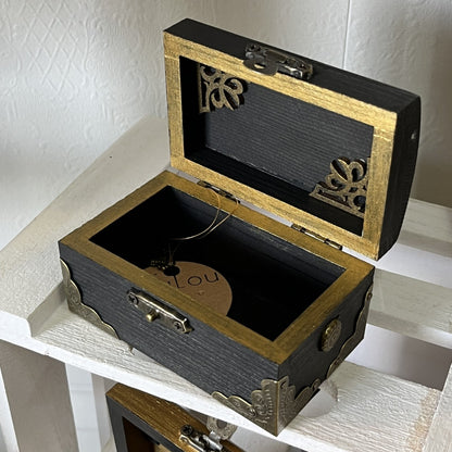 Decorative wooden gold and black ornate box with open lid.
