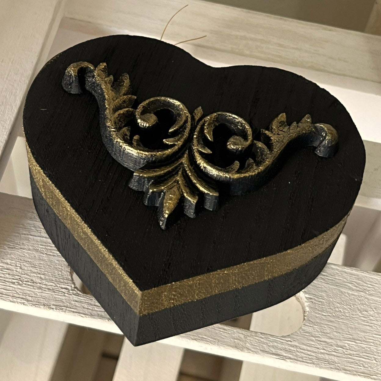 Decorative heart-shaped box with gold accents on a wooden surface